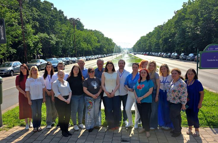 Group photos of participants from the SHARING project event, standing on a tree-lined avenue in Bucharest, Romania. Participants are smiling and engaged in informal conversation, showcasing the project's collaborative spirit and diverse representation.