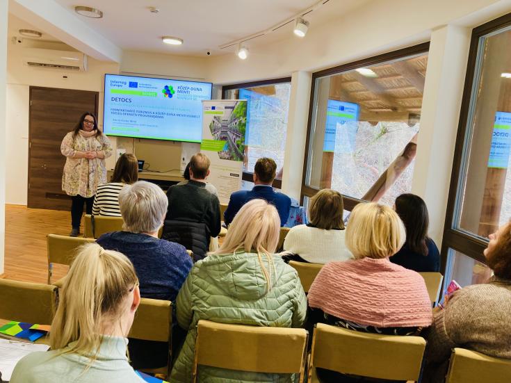 A woman giving a presentation to a group of people sitting on chairs