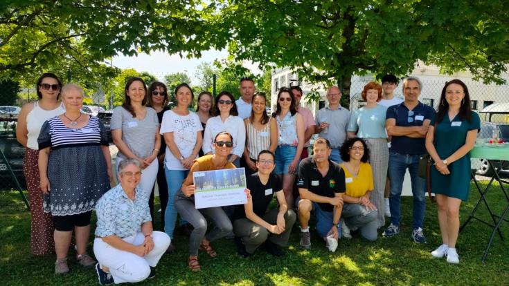 Group of people standing under green trees in a two row in summer 2024 in Aix-les-Bains, France.