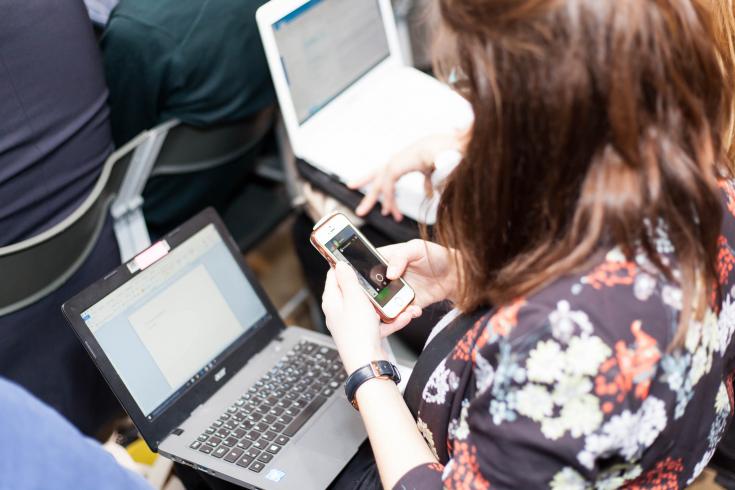 Woman checking her phone while using her laptop Woman checking her phone while using her laptop