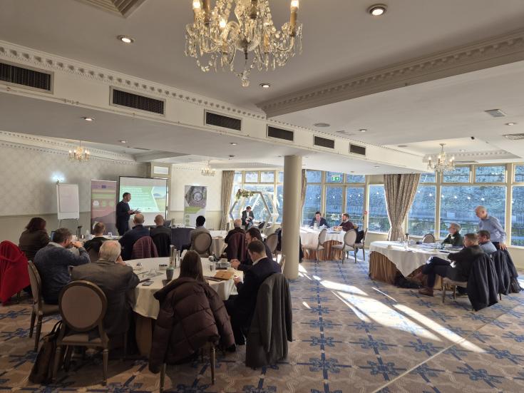 Photo of the meeting room with participants listening to presentations