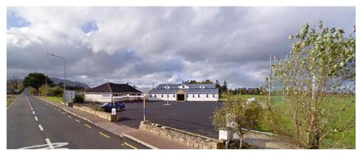 An asphalted country road with a building on the side. 