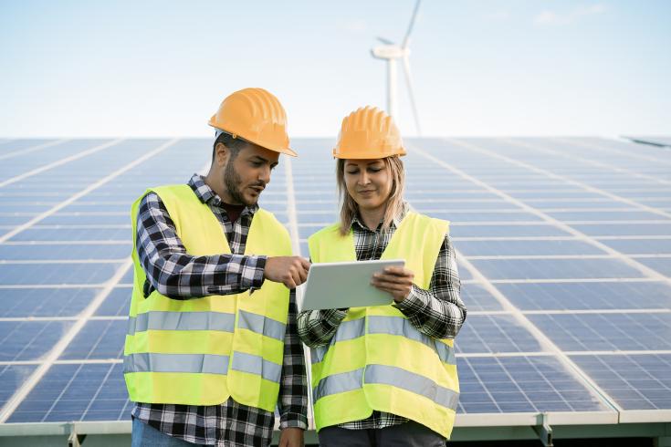 Male and female construction workers in front of solar panels
