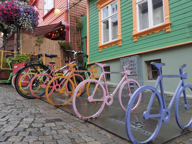 Line of colourful bikes against a green wall