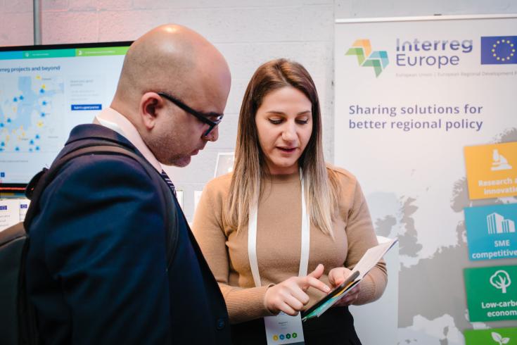 PLP staff helps event attendee at 'Europe, let's cooperate' 2019. Staff member helps an event attendee with their questions.