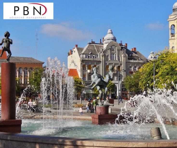 a city center with a fountain, buildings, statues