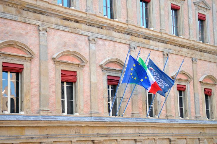 Building with 3 flags of the European Union, Italy and Bologna.