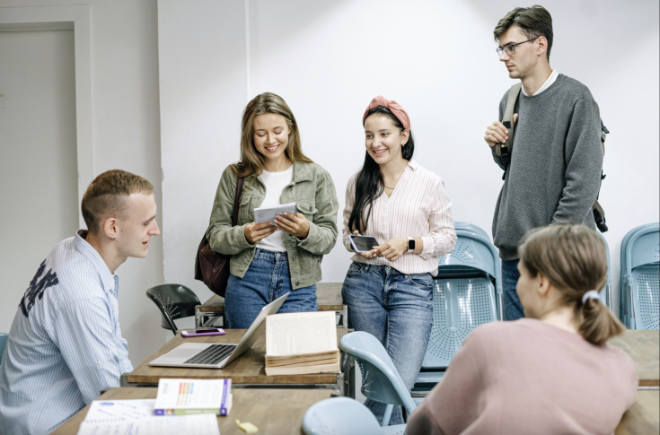 People sitting and standing around table People sitting and standing around table
