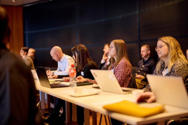 People sitting at a table with laptops in front of them People sitting at a table with laptops in front of them