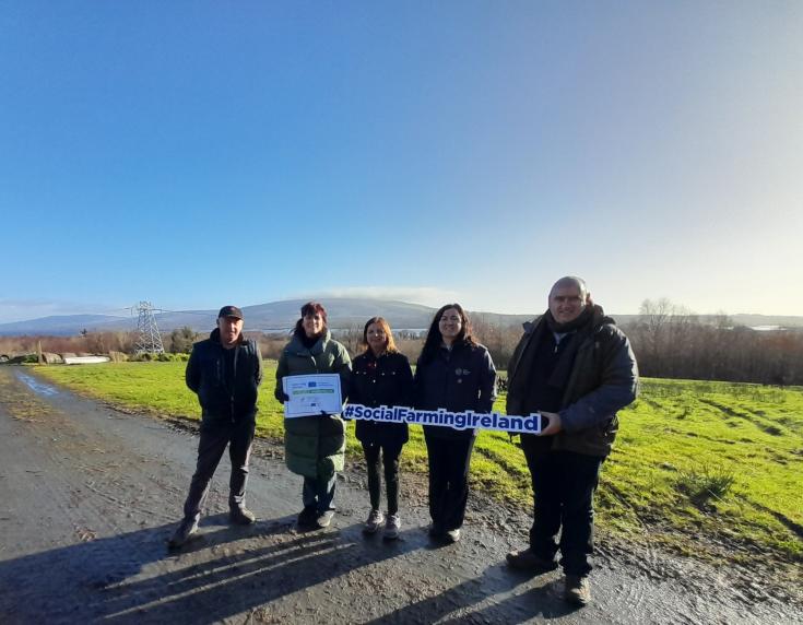 Five adults holding a banner standing on a flat landscape