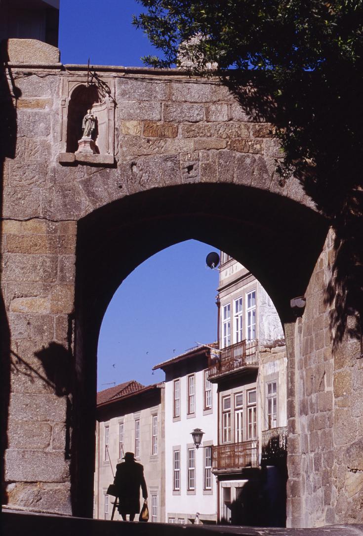 Porta de S. Joao Viseu Portugal Eldery lady passing under an old granite door with coat of arms