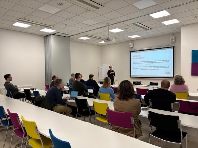 people gathered  in a room, looking at presentation