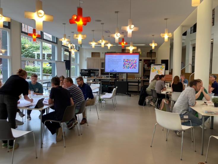 People are sitting around tables, engaging in a discussion during a session. 