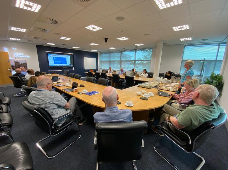 A group of people in a meeting room hearing a presentation