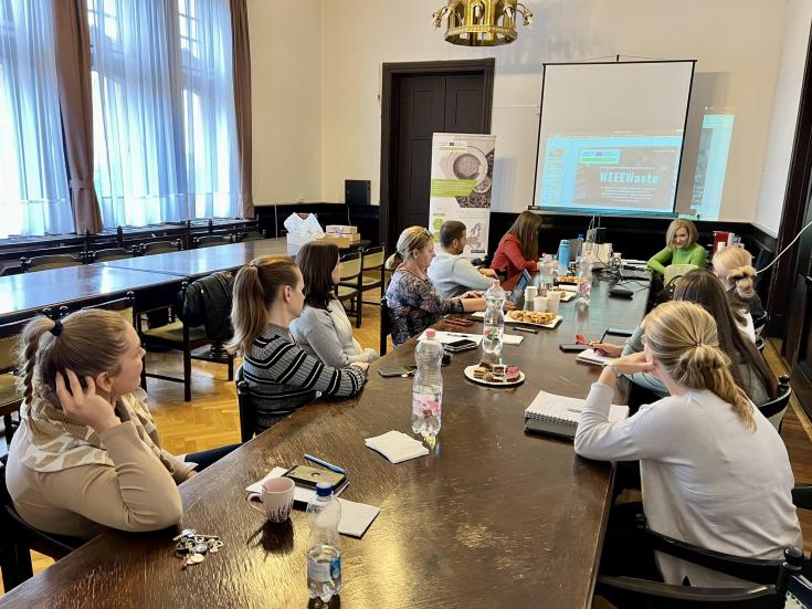 Participants during the 4th stakeholder meeting of the Hajdú-Bihar County sitting around a table, listening to a presentation on the project activities from the previous period
