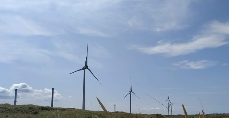 Wind energy turbines with a cloudy blue sky