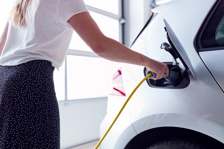 Woman charging electric vehicle