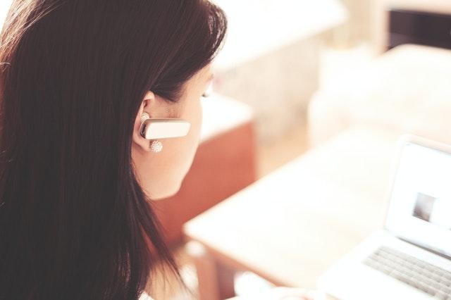 Woman working behind computer with headphones