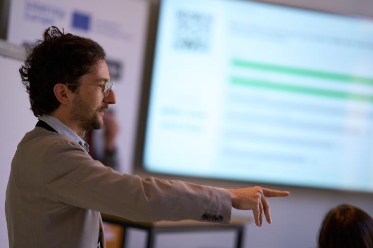 Man in front of a screen pointing at someone