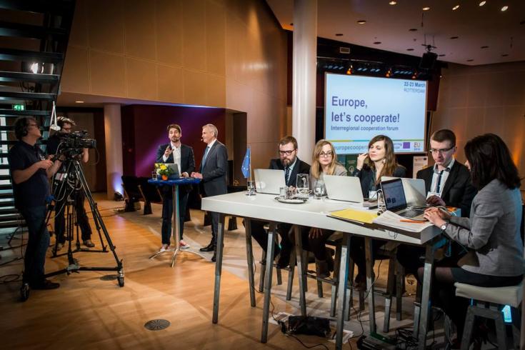 People writing on laptops in front of a Europe let's cooperate screen People writing on laptops in front of a Europe let's cooperate screen
