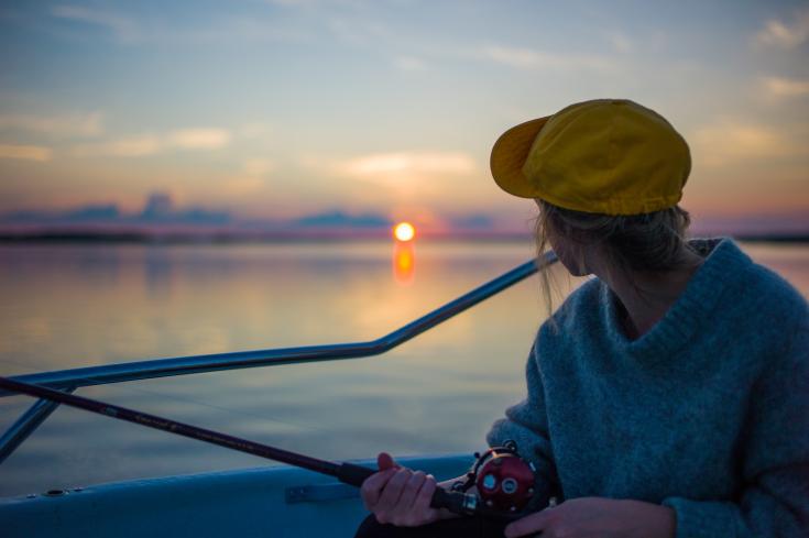 Man holding black fishing rod while facing body of water
