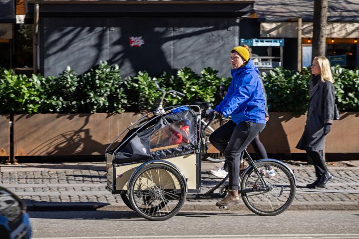 Women cycling on cargo bike in autumn/winter Women cycling on cargo bike in autumn/winter