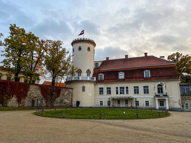 Castle in autumn park with colourful trees and leaves on the ground in October in Cesis, Latvia