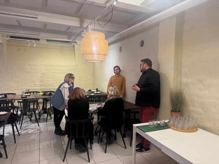 People are sitting around a table, engaging in a discussion during a meeting. 