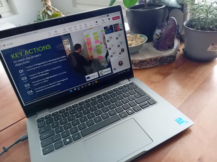 Laptop on a table with an online seminar presentation rolling. In the screen there is a slide with topic of key actions.