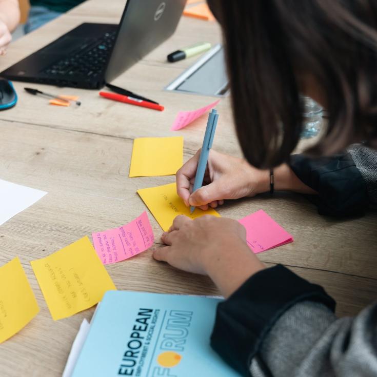 person writing on a post-it note