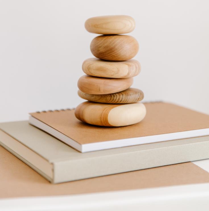 A number of wood-coloured stones above a book and notepaper