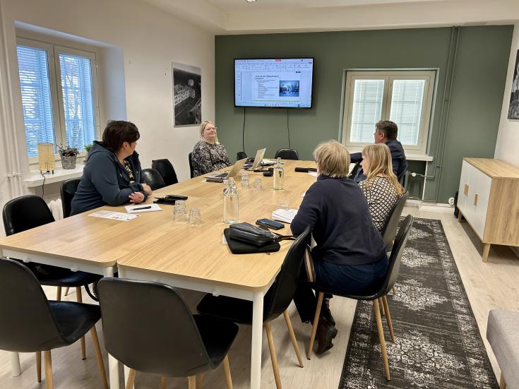 5 people around a table having a meeting
