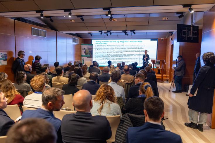 A view from the back of the room to the audience and a speaker.