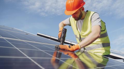 Construction worker installing solar panels on roof