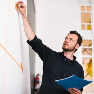 Man putting post it on board Man putting post it on board