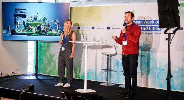 Green Screen is a RegioStars finalists in 2023 two people standing on stage holding microphones and giving a presentation