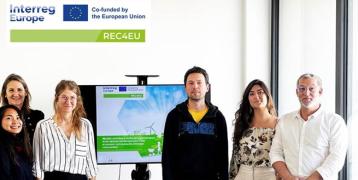 Group of people standing in front of a screen - logo REC4EU