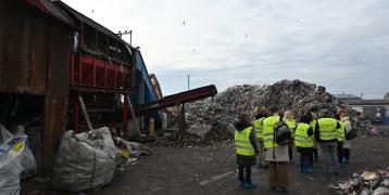 Group of people with yellow vests visiting a waste facilit