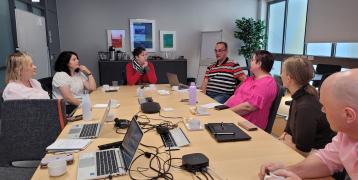 Stakeholder group members sitting around a table, engaged in discussion during the INVOLVIM project meeting.