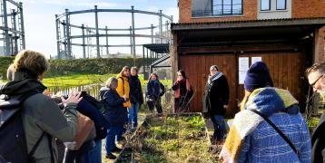 People standing outside on a sunny but cold day looking at a greening project