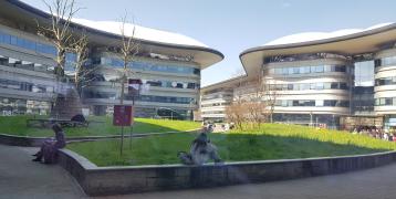Modern wave-shaped buildings around courtyard with grass and a few people