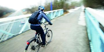 Man bicycling over a bridge in winter time