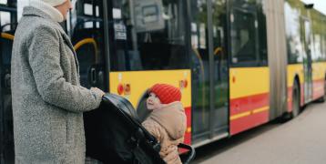Woman and child in buggy with a bus in the background