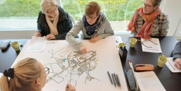 Older adults sitting around a table, working to address loneliness from a neighbourhood perspective