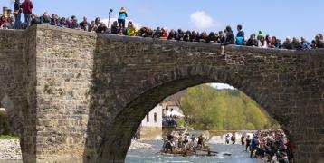 Group of people on a bridge watching a show on the river