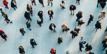 Looking down from above, we see people in a big waiting lounge - all standing up or walking.