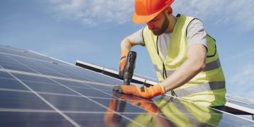 Construction worker installing solar panels on roof Construction worker installing solar panels on roof