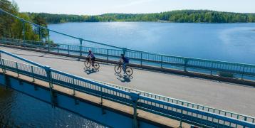 Two cyclists crossing a bridge in a lake scenery