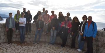 persons in gathered around a low stone wall with sea view