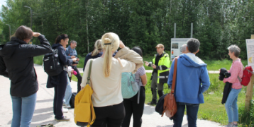 People standing outside, listening to an expert's presentation about the destination